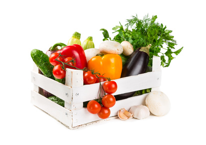 Fresh vegetables in a painted wooden box isolated on white background